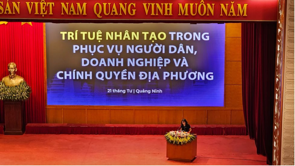 Quang Ninh provincial hall session titled 'Artificial intelligence serving citizens, businesses and local government', with a speaker at the podium in front of a large screen.