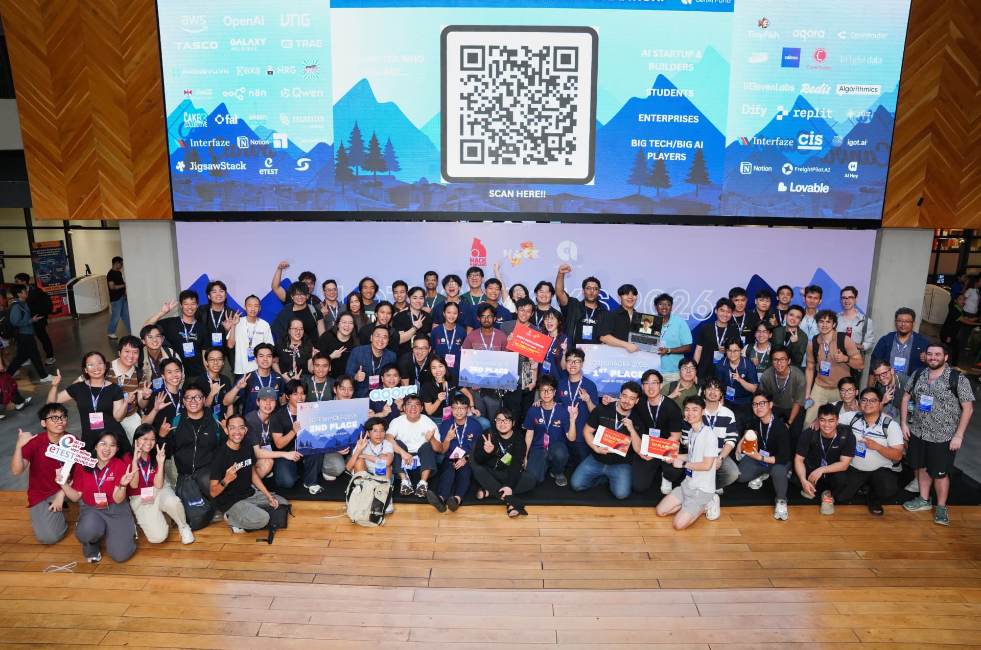 LotusHacks 2026: the full cohort of participants, mentors and partners on stage with 1st, 2nd and 3rd place boards after Vietnam's largest-ever AI hackathon.